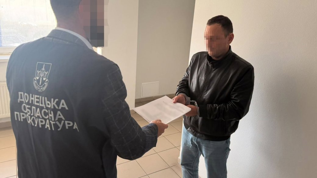 Представник Донецької обласної прокуратури вручає документ чоловікові з прихованим обличчям